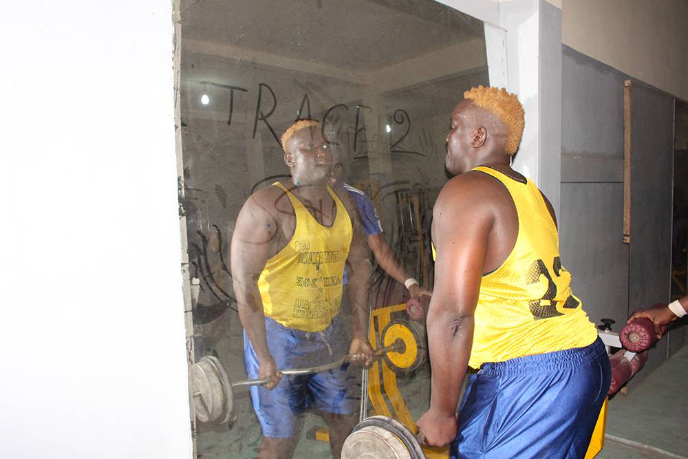 A wrestler lifting weights at the gym to achieve the muscular body required by the sport