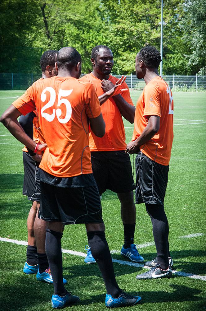 Ifechi and Ifeanyi (both on the right) discuss a plan for the second half of the game (their side trailed 0-3 with the team composed of active players), while two of their teammates stand close and listen. Ifechi and Ifeanyi, who have been in Poland for almost a decade, are prominent figures in the park community, and both served in the past as presidents of PolBlack. Warsaw, Summer 2016. (Photo Paweł Banaś)